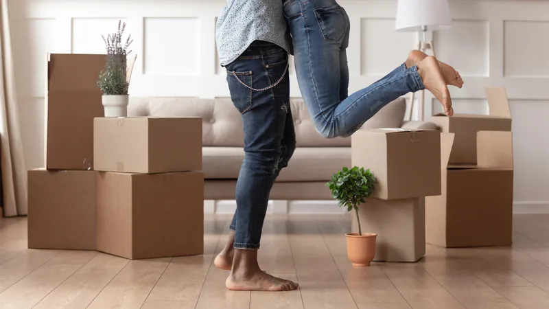 A person carrying moving boxes into an empty new home