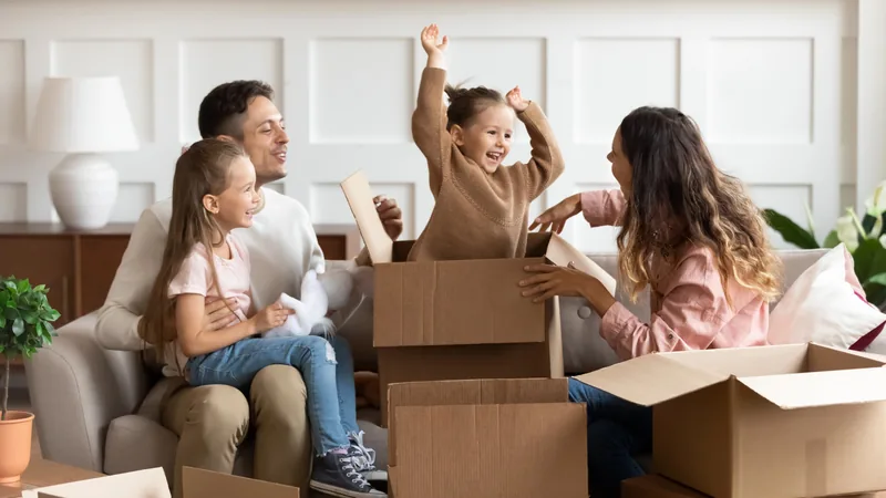 A family unpacking moving boxes on the sofa of their new home