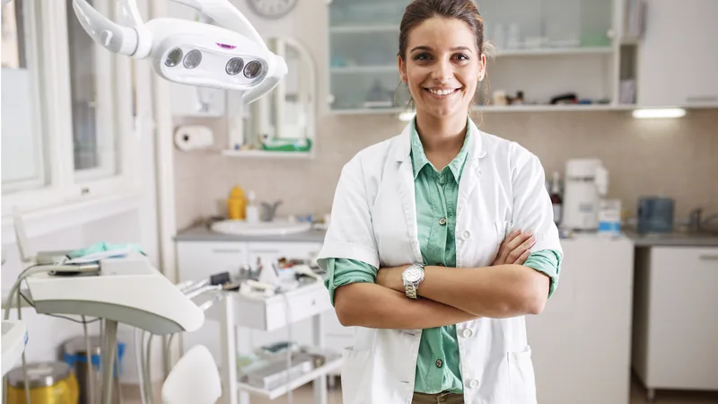 A dentist standing in her surgery with her arms folded